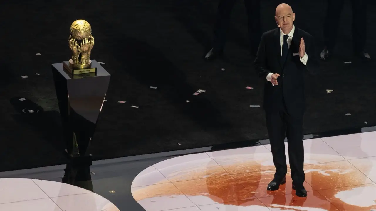 FIFA president Gianni Infantino stands beside the FIFA World Cup trophy.