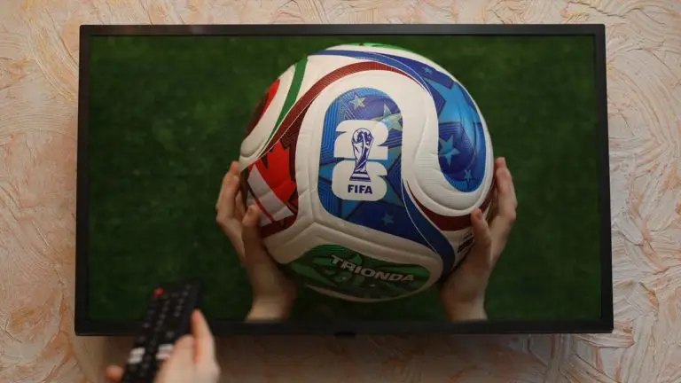 World Cup ball shown on a television screen as a viewer holds a remote control