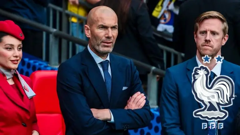 Zinédine Zidane watches from the stands beside a large France football crest