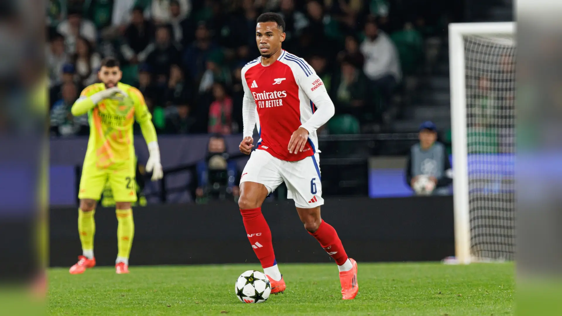 An Arsenal defender in the red-and-white home kit carries the ball during a match