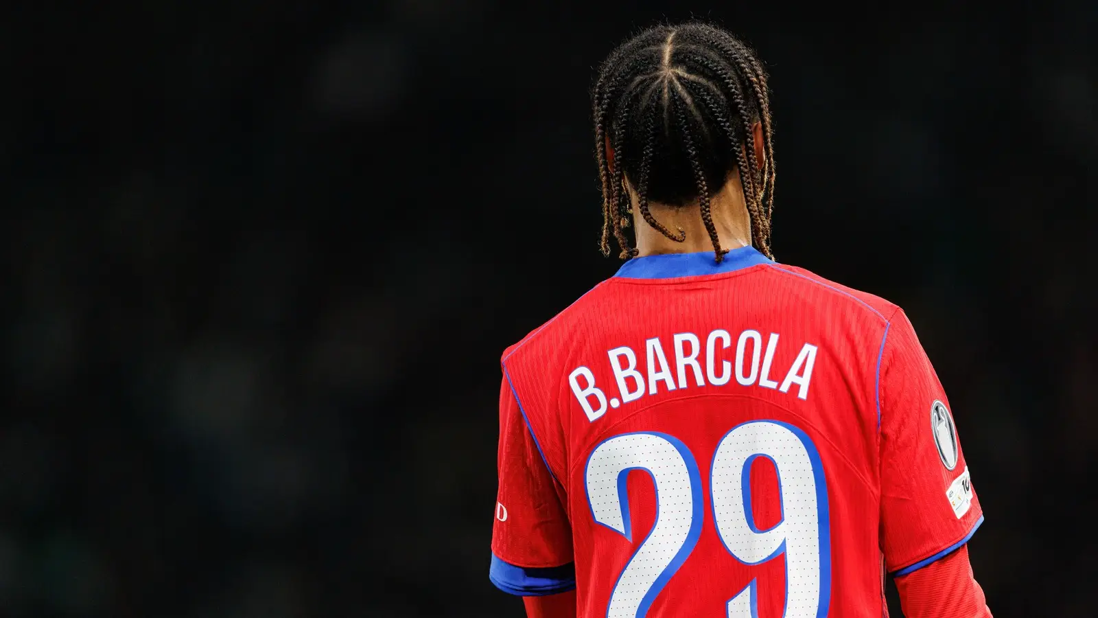 Bradley Barcola seen from behind wearing a red Paris Saint-Germain No. 29 shirt