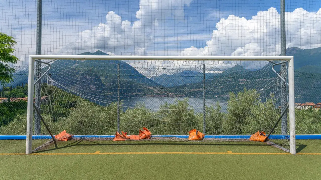 Italian football training ground overlooking an Alpine lake and mountains in Italy