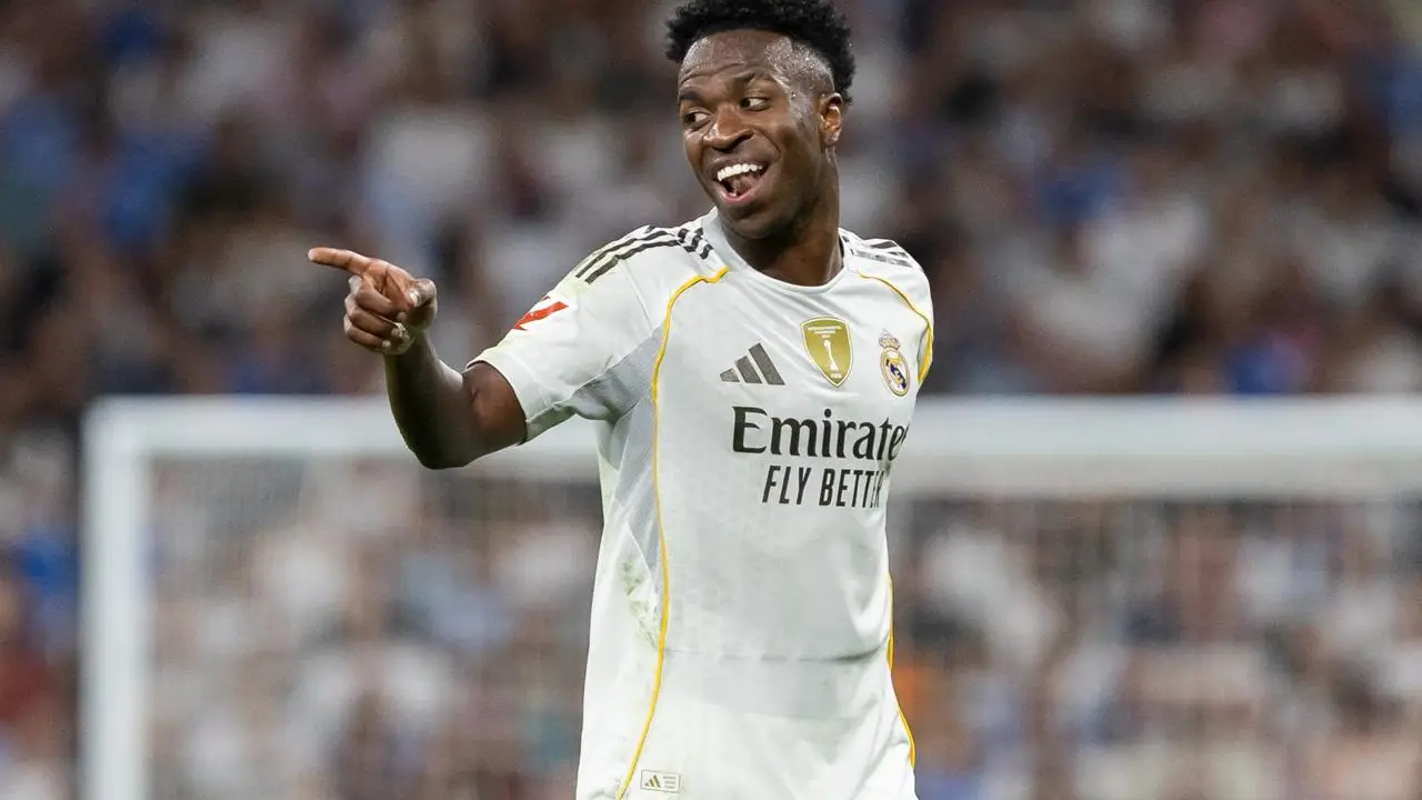 Vinícius Júnior smiles and points while wearing Real Madrid’s white kit