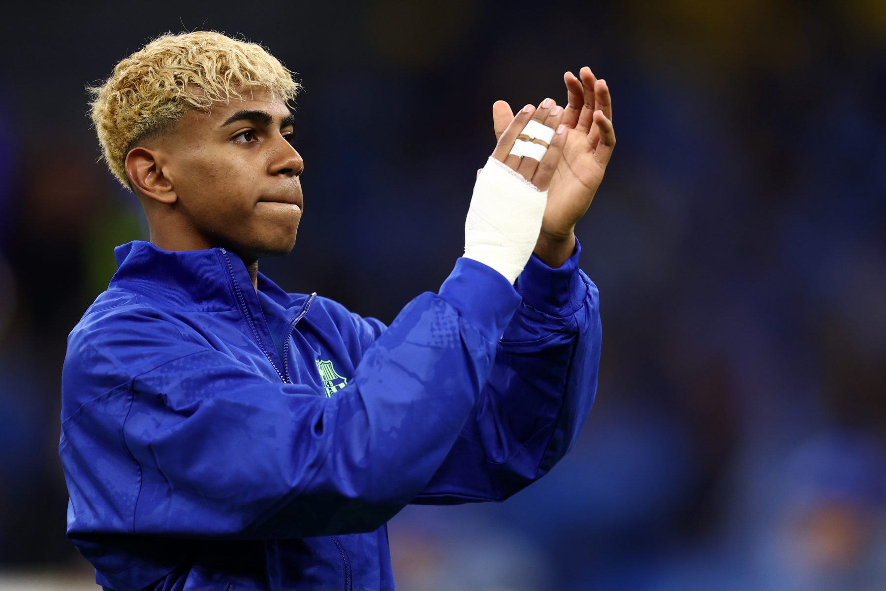 Lamine Yamal applauds while wearing an FC Barcelona jacket.