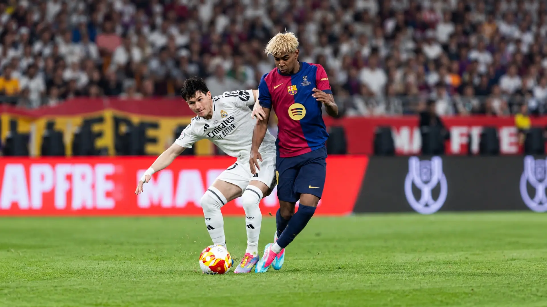 Lamine Yamal controls the ball for Barcelona as a Real Madrid defender challenges him in El Clásico.