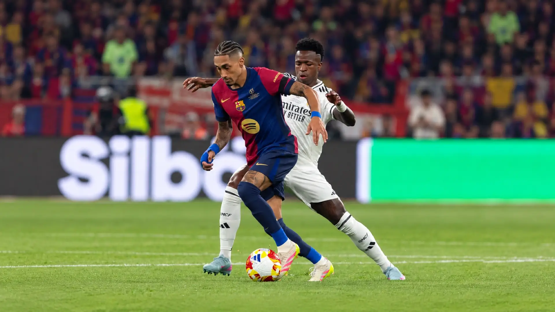 Raphinha shields the ball from Vinícius Júnior during Barcelona versus Real Madrid in El Clásico.