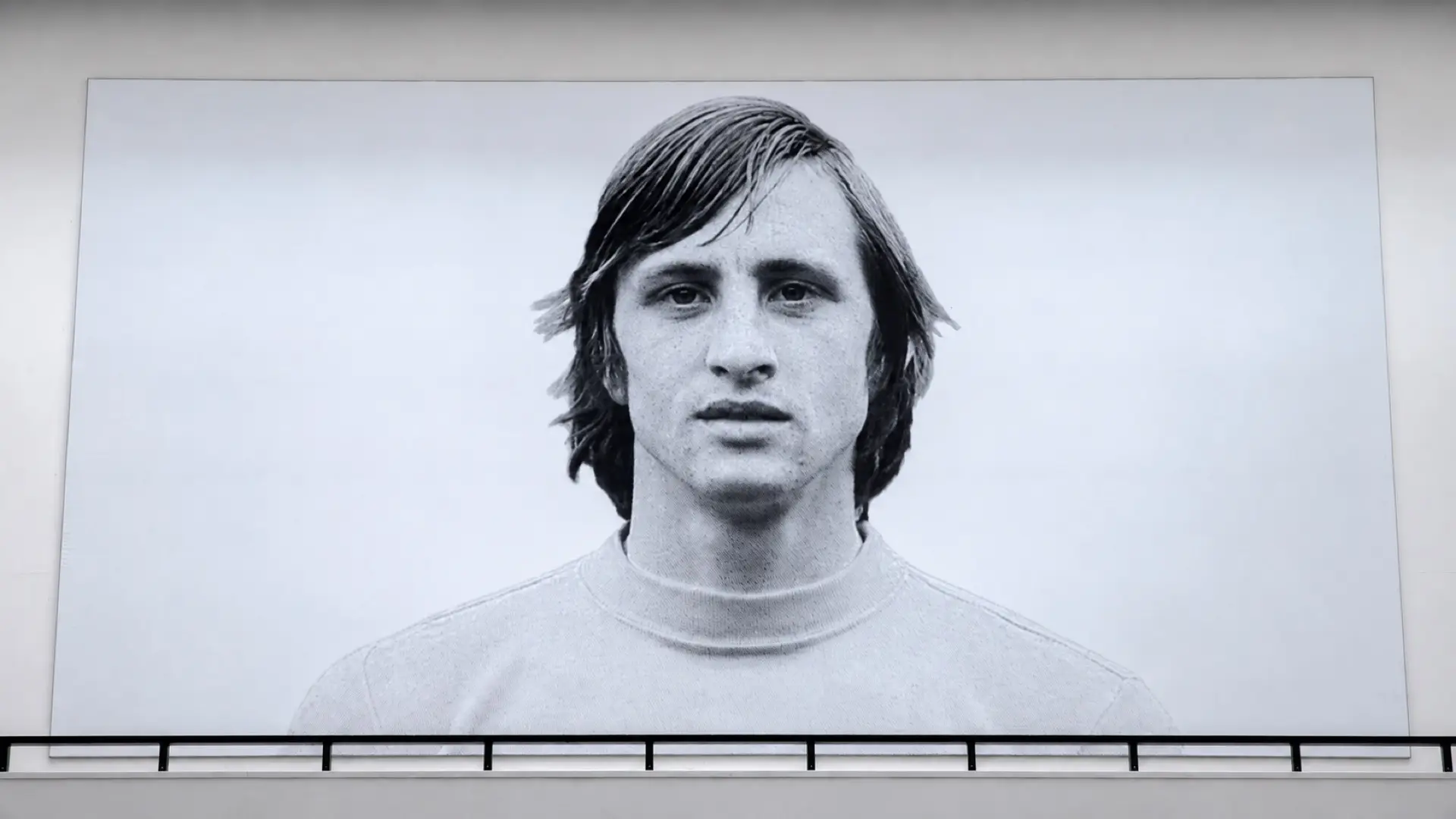 Large black-and-white football portrait mounted on a wall above a railing.